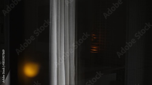 During the night at home, a sad blonde woman looks out the window. A deeply emotional and poignant scene expressing loneliness, reflection, melancholy, and inner pain.