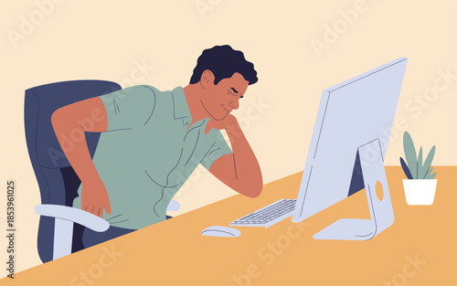 A man sitting at a desk, working on a computer with a tired expression in an office environment from a slightly angled viewpoint