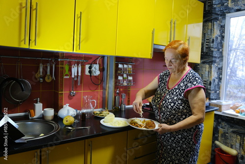Senior woman cooking food on the stove in kitchen. High quality photo