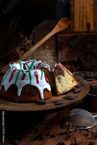 Vanilla and chocolate pudding covered with white sugar sauce, decorated with red and green icing and coffee beans in a kitchen with wood 