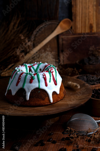 Vanilla and chocolate pudding covered with white sugar sauce, decorated with red and green icing and coffee beans in a kitchen with wood 