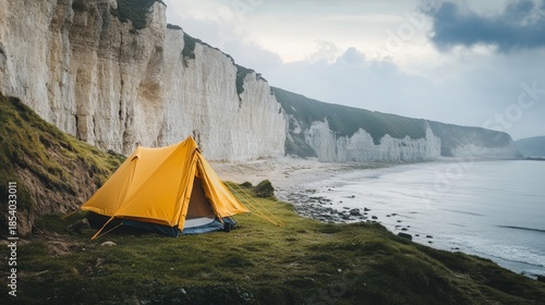 A vibrant yellow tent stands against a dramatic cliffside by the ocean. The serene landscape invites exploration and relaxation. Experience nature like never before. Generative AI