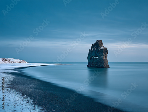 Dramatic seascape with rugged rock formation on black sand beach