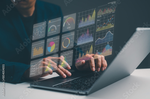 A person interacts with a laptop displaying holographic graphs and charts, showcasing data analysis and digital insights.