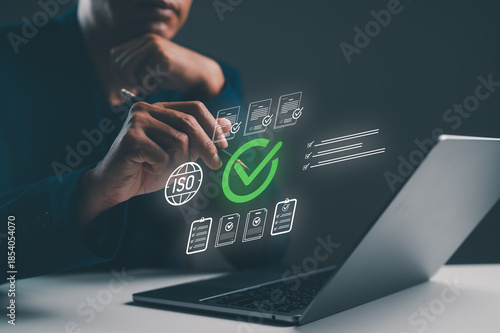 A person interacts with a laptop, displaying digital icons related to ISO certification and compliance checks, emphasizing technology and quality assurance.