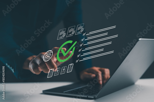 A person interacts with a laptop, displaying digital checkmarks and ISO symbols, suggesting quality assurance or compliance processes.