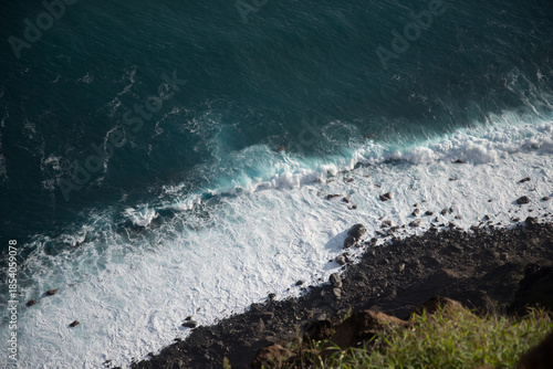 Aerial view of rugged coastline with crashing waves on a sunny day
