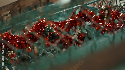 Shiny red metallic tinsel garland drapes across a textured green backdrop in a festive display of sparkle