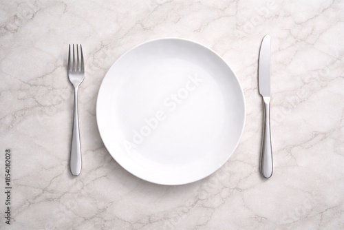 明るい白大理石のテーブルに白い皿とカトラリーを並べたフラットレイ背景