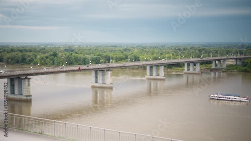 Wallpaper Mural ferry passing beneath concrete highway bridge during cloudy weather, pilot navigating between massive pillars, inspector checking structure, commuters photographing river, wake reflecting pillar Torontodigital.ca