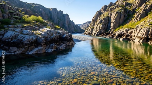 Sunlit Canyon River: Crystal Clear Emerald Waters Revealing Pebbles on Riverbed.