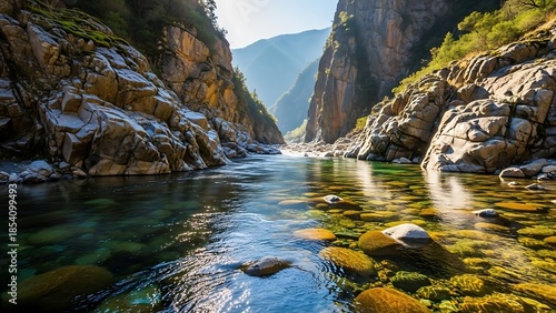 Sunlit Canyon River: Crystal Clear Water Reveals Mossy Riverbed Rocks and Majestic Walls.