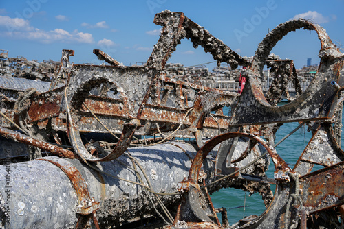 Rusty, barnacle-covered metal pipes at an abandoned harbor symbolize the environmental impact of industry on marine ecosystems.