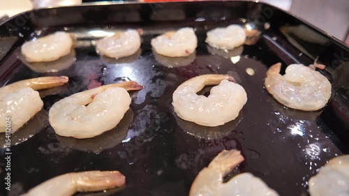 Raw shrimp placed on black grill tray
