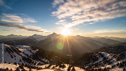 Stunning sunrise over snow-covered mountains, with bright sunbeams bursting across the sky.