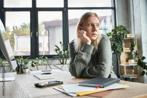 Fotografi Stylish non binary individual in a modern workspace, reflecting on creativity an