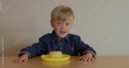 A joyful child is happy about a donut on a plate, smiling and dancing happily. The pleasures of childhood. Unhealthy snacks.