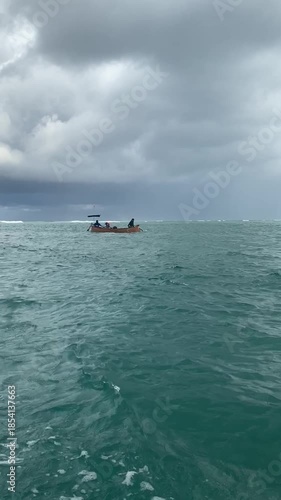 Vertical shot of a traditional wooden boat sailing on the turquoise ocean. Essential inter-island transportation and local maritime lifestyle in a tropical archipelago.