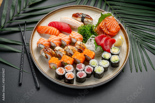 Assortment of Sushi, Sashimi, and Maki Rolls on Plate. A beautifully arranged platter features a wide assortment of colorful sushi, sashimi, and maki rolls