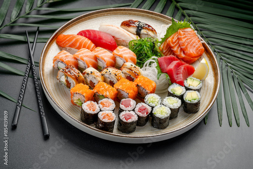 Variety Platter of Sushi, Sashimi, and Maki Rolls. A circular plate features a rich variety of nigiri, sashimi, and maki rolls, showcasing tuna, salmon, eel, and vegetable fillings.