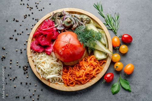 Assorted Fermented and Pickled Vegetables Appetizer Platter. An overhead view of a wooden platter displays assorted fermented and pickled vegetables, including cabbage, carrots, and mushrooms.