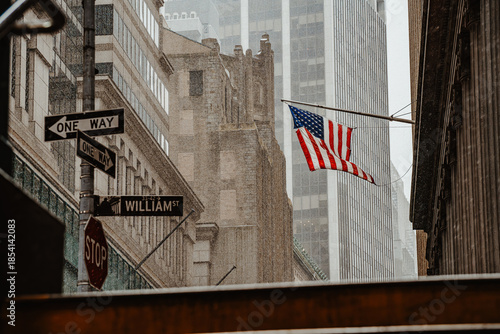 Street view under rainfall in urban area. Pedestrians and architecture visible through wet conditions