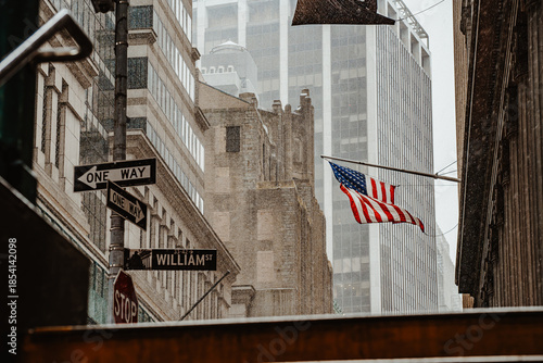 Rainy street with US flag in New York. Urban downtown setting with traffic signs and American flag
