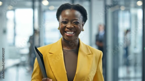 A young positive business woman holds a folder and walks through the office