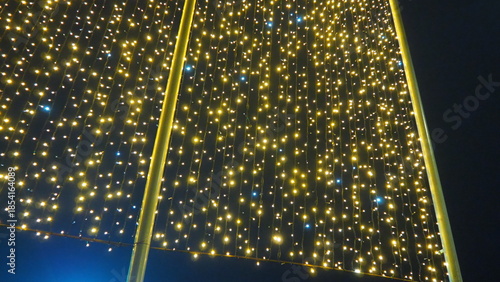 Flashing yellow and blue modern garlands of light bulbs in evening darkness. Theme of the New Year and Christmas. A background of sparkling light bulbs. Festive mood. Window and street decoration
