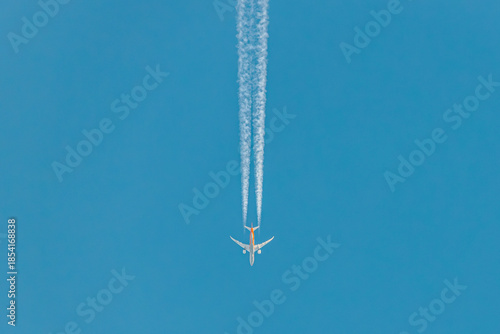 Photos Airplane flying high in a clear blue sky, leaving a white contrail behind, showc
