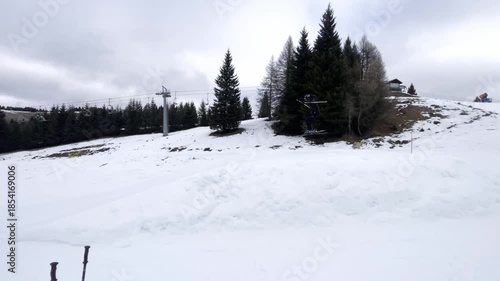Freestyle Skier Performing a Jump Trick on a Snowy Slope in Winter Ski Resort, Action Sports and Adrenaline in Alpine Mountains, Cloudy Day with Pine Trees
