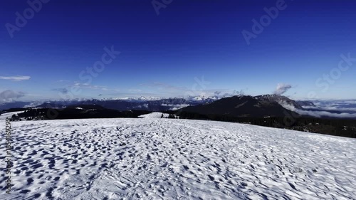 Panoramic View of Snowy Mountain Peaks Under Clear Blue Sky, Stunning Winter Alpine Landscape with Valleys and distant Ranges, Sunny Day in the Dolomites or Alps