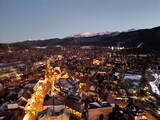 Zakopane - Polska - stolica Polskich Tatr nagrana wieczorem z drona. Swiatła miasta i góry w tle zimową porą podczas zachodu słońca