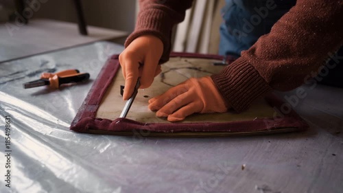 Close up of furniture restorer hands removing old upholstery from vintage wooden chair in workshop