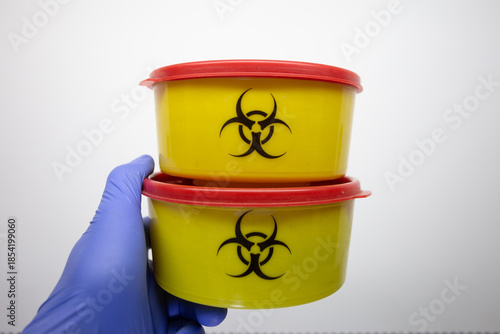 A scientist holds containers with biohazardous substances on a white background - a biohazard sign.