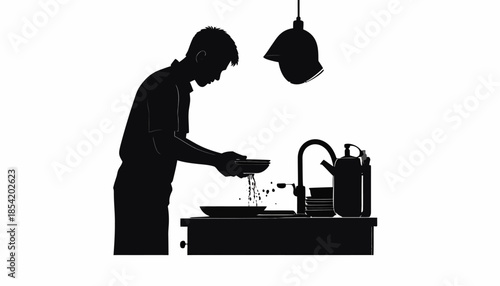 Silhouette of a person washing dishes in a kitchen sink under a lamp.