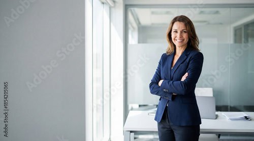 Beautiful hispanic senior business woman with crossed arms smiling at camera. European or latin confident mature middle age leader female businesswoman standing at office workplace, copy space. 