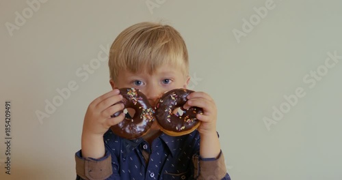 Boy with donuts and playful expression, Child laughing while modeling with colorful donut props inside