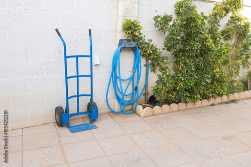 Blue hand truck and garden hose storage backyard