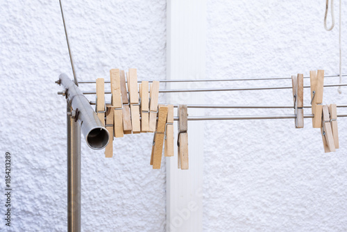 Wooden clothes pegs on metal drying rack against white wall
