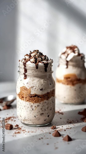 Dessert preparation with layers of ice cream and chocolate sauce in a sunny kitchen