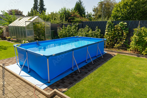 A large 2x4 meter swimming pool with clear water sits on a green lawn in the garden. A beautiful garden with a greenhouse and various plants provides a relaxing area for the whole family.