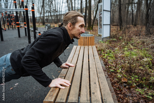 Bild auf Leinwand man performing incline pushups outdoors, athletic individual doing incline pushu