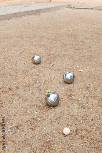Pétanque metal boules and jack resting on sand