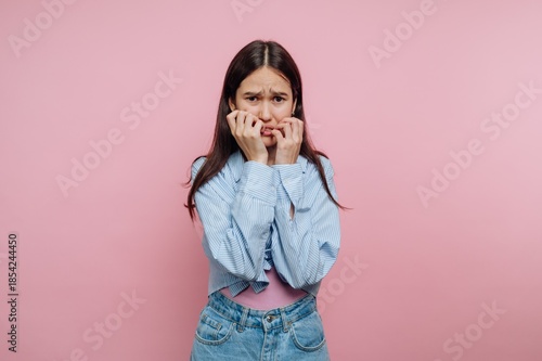 Fotografija Young person expressing discomfort in front of a pink background with a worried