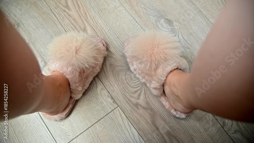 A first-person view from above of women's feet in fluffy slippers. Women's feet and their care in winter.