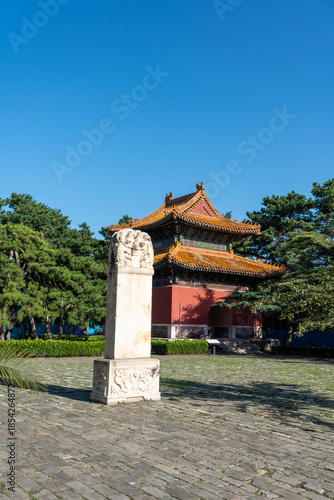 Photography Vertical shot of a weathered stone stele standing in a green courtyard at the Ming Tombs complex