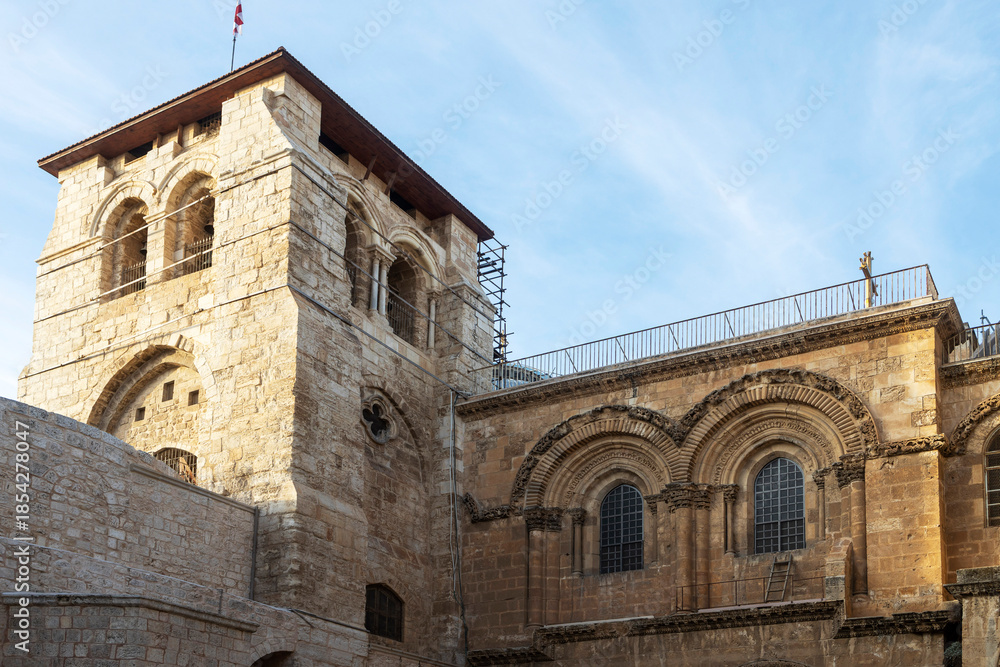 Obraz premium Jerusalem, Israel, December 22, 2025, Exterior view of the Church of the Holy Sepulchre featuring the medieval bell tower and stone facade in Jerusalem.