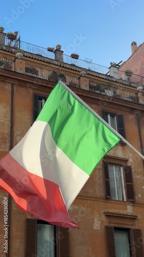 National Day of Italy.Close-up view of an Italian flag on a building balcony with ornate details and wooden shutters, captured in sunlight.