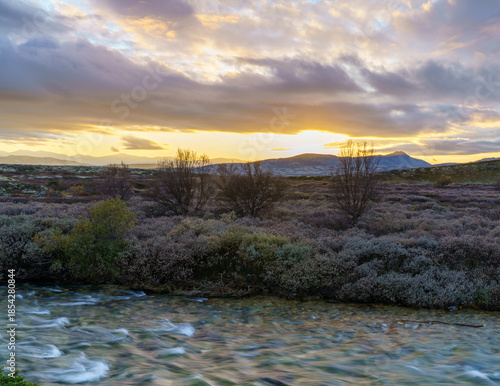 Arctic tundra river at dusk with mountain backdrop